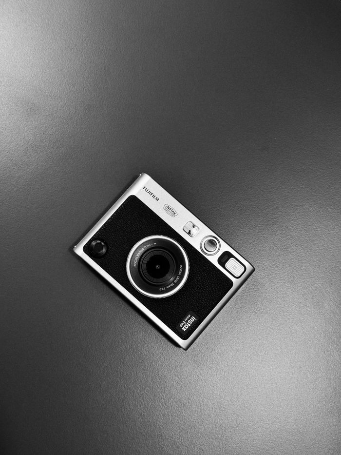 A close-up shot of a vintage instant camera with a minimalistic design on a black surface.